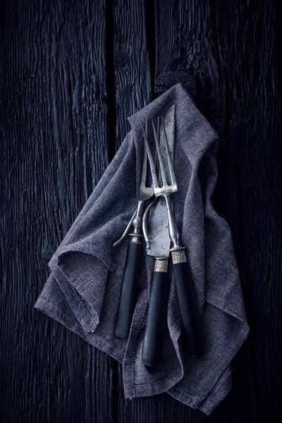 Talheres à moda antiga na toalha de cozinha em um backgro de madeira preta — Fotografia de Stock