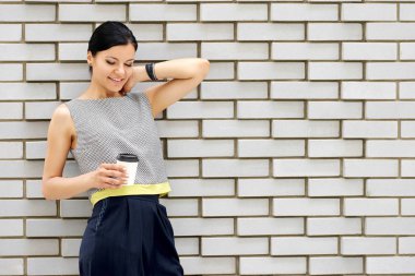 Gülümseyen duvarın yanında kahve ile esmer kadın