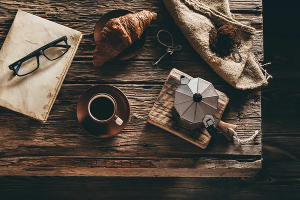 Taza de café e ingredientes en la vieja mesa de madera en la ventana de noche — Foto de Stock