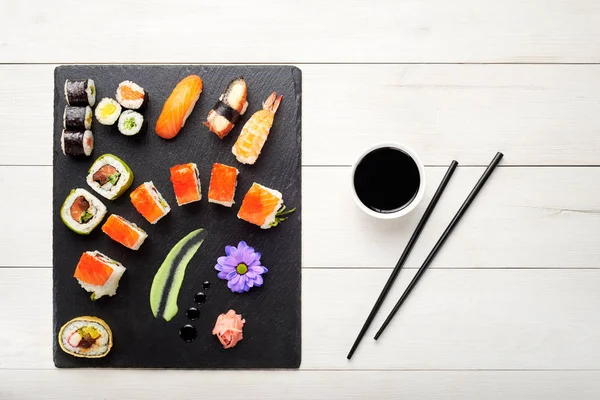 Sushi, pálcika, és szójaszósz, fekete kő lemez felülnézet — Stock Fotó