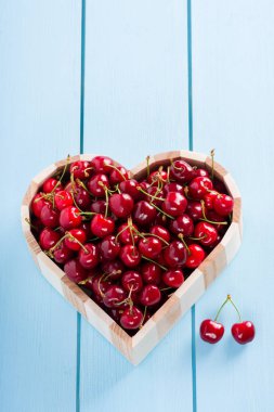 kiraz mavi ahşap masa üstü bir kalp kutusunda görüntülemek