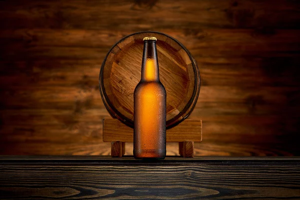 Garrafa de cerveja gelada e barril velho em fundo de madeira — Fotografia de Stock