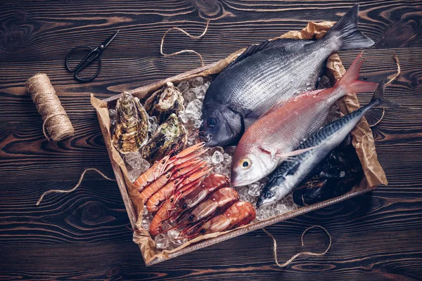 Čerstvé španělské ryby a mořské plody v dřevěné krabici na dřevěný stůl — Stock fotografie