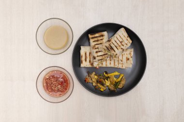 Tahta bir arka planda Shawarma ve soslar