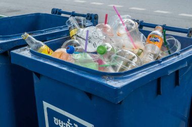 Çöplerle dolu mavi çöp tenekesi. Çöp plastik kirliliği.