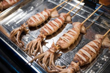 Bangkok, Tayland 'daki gece pazarında ızgara kalamar satıyor..