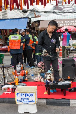 Bir adam Bangkok 'taki Chatuchak hafta sonu pazarında Manop The Puppet sokak performansını sergilediğini görebilir..