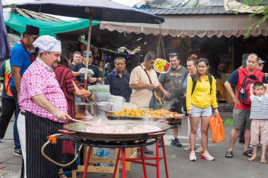 Chatuchak hafta sonu pazarında çeşitli gıda türleri satılıyor, insanlar çevreyi keşfedip yiyecek satın alırken görülebiliyor, dünyanın en büyük hafta sonu pazarlarından biri..