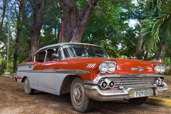 Santa Clara, Cuba - 04 de septiembre de 2016: Coche clásico Chevrolet rojo americano estacionado bajo palmeras en Santa Clara Cuba - Serie Cuba 2016 Reportaje — Foto de Stock