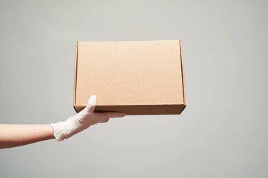 Hands in latex gloves holding cardboard box