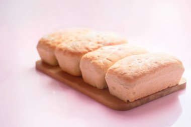 Ahşap tezgahta taze ev yapımı ekmek. Pembe arka planda izole edilmiş. Kopya alanı da var.