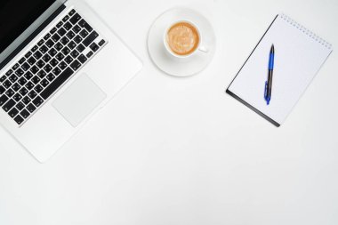 Dizüstü bilgisayarı olan minimum çalışma alanı, beyaz arka planda bir kalem ve bir fincan kahve olan Notepad. Yukarıdan manzara. Düz yatıyordu.