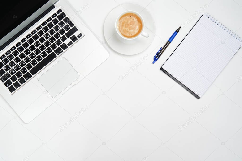 Minimal workspace with a laptop, Notepad with a pen and a Cup of coffee on a white background. The view from the top. Flat lay.