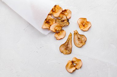 Ev yapımı organik kuru meyve cipsleri kağıt külahta ya da beyaz arka planda düz koni şeklinde poşet şeklinde dilimler.