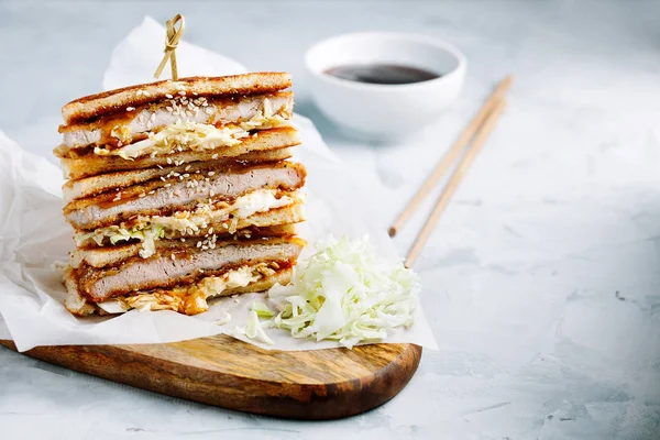 Katsu Sando japanese cutlet sandwich with deep fried pork,cabbage,mayonnaise and tonkatsu sauce on a light background