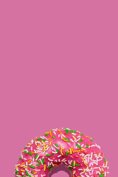 Rosquillas dulces de frambuesa o rosquillas con glaseado y con coloridas salpicaduras de azúcar sobre fondo rosa pastel —  Fotos de Stock