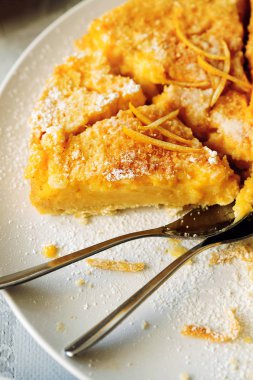 Traditional English lemon pudding cake with lemon twist and powdered sugar on a white plate