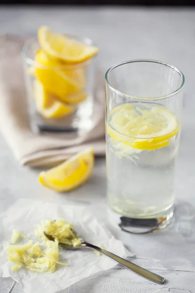 Zelfgemaakte verfrissende geïnfundeerde detox water of limonade in glazen flessen met geraspte gember en citroen op grijze achtergrond — Stockfoto