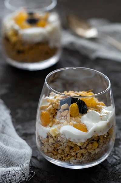 Hemlagad ekologisk färsk grekisk yoghurt parfait med granola, nötter och russin i glas på grå betong bakgrund — Stockfoto