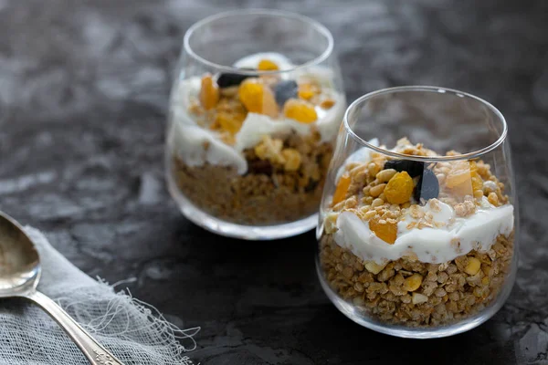 Hemlagad ekologisk färsk grekisk yoghurt parfait med granola, nötter och russin i glas på grå betong bakgrund — Stockfoto