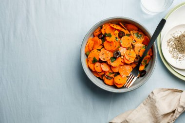 Geleneksel Fas usulü havuç salatası Kuzey Afrika vegan yemeği doğranmış maydanoz ve gri tabakta zeytin.