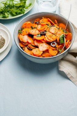 Geleneksel Fas usulü havuç salatası Kuzey Afrika sebze yemeği doğranmış maydanoz ve gri tabakta zeytin.