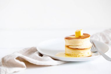 Yumuşak Japon sufle krepleri, tereyağı ve akçaağaç pekmezli sıcak kekler ya da açık beyaz arka planda bal sosu.