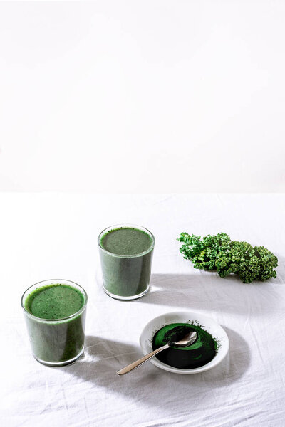 Color green spinach kale apple yogurt smoothie with spirulina on white background with shadow