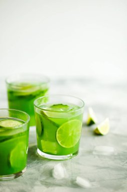 Ev yapımı buzlu kibrit yeşil çay ya da salatalık ve açık gri arka planda limonata.