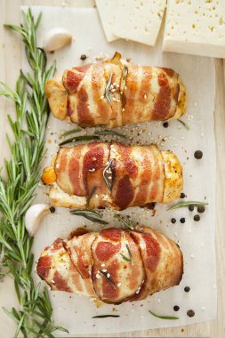 Bayram yemeği için ızgara pastırmaya sarılı sebze ve peynirli tavuk dürümleri. Dikey yönelim, üst görünüm, düz yatış.