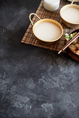 Makgeolli pirinç şarabı koyu arka planda Kore 'nin en eski mayalanmış alkollü içkilerindendir. Sağlıklı Asya içkisi. Dikey oryantasyon, kopyalama alanı. Seçici odak