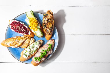 Farklı tatlı ve lezzetli tabaklar ve beyaz arkaplanlı çeşitli brushetta ya da tapas setleri. Sebze ve meyve görünümlü açık tost sandviçi düzleştirilmiş. Yatay yönelimli.