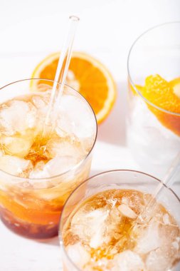 Soğuk kahve kokteyli, portakal kabuğu ve cam pipetle yakın plan. Beyaz arka planda narenciye katkılı bardak. Yaz aylarında alkolsüz içecek kavramını tazeliyor. Dikey yönelim