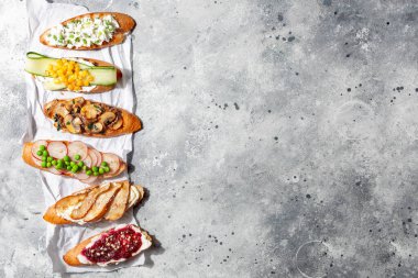 Çeşitli İtalyan aperatifleri bruschetta ya da tapas seti üzerinde farklı tatlı ve lezzetli gri beton kaplama. Üst manzara, kopyalama alanı.