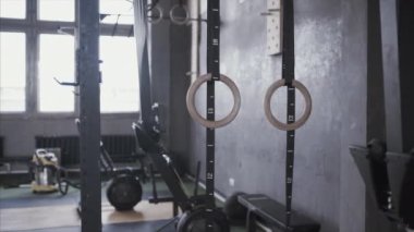 Jimnastik yüzükleri spor salonunda asılı duruyor. Pilates ve Crossfit, atletizm ve jimnastik için eğitim ekipmanları.