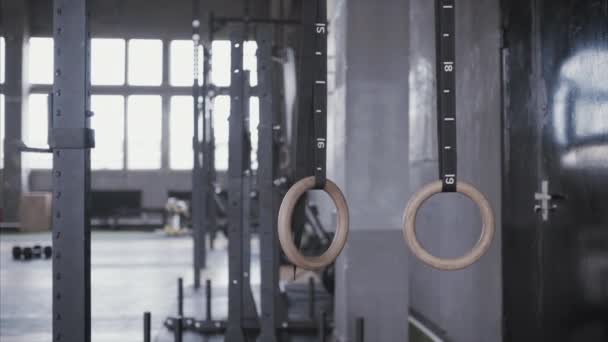 Turnringe hängen in Turnhallen. Trainingsgeräte für Pilates und Crossfit, Leichtathletik und Turnen. — Stockvideo