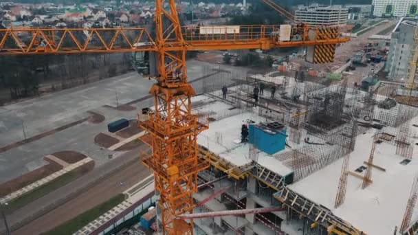 Zicht vanuit de lucht, drone in de buurt van kraan op bouwplaats en bouwers. — Stockvideo