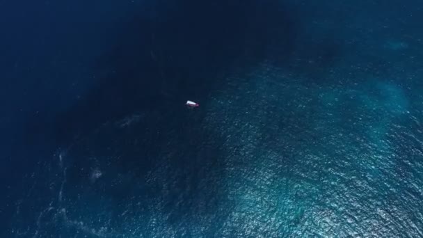 Vista superior desde arriba yate anclado barco flotando en la escorrentía del océano o crucero se encuentra en aguas azules del mar con arrecife de coral — Vídeo de stock