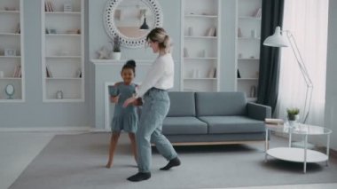 Önemseyen anne beyaz gömlek giyip, güzel vakit geçiriyor. Çok uluslu aile kavramı. Çok uluslu, mutlu anne, zıplayan komik Afrikalı kız.