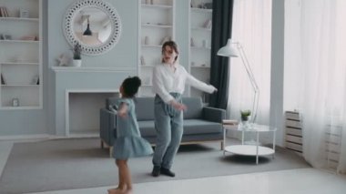 Muhteşem neşeli anne zıplayan komik çocuk Afrikalı kız kanepede birlikte dans ediyor şefkatli anne beyaz gömlek giyip çok uluslu aile kavramını giyip eğleniyor.