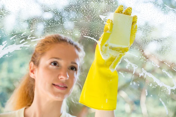 Happy woman in gloves cleaning window
