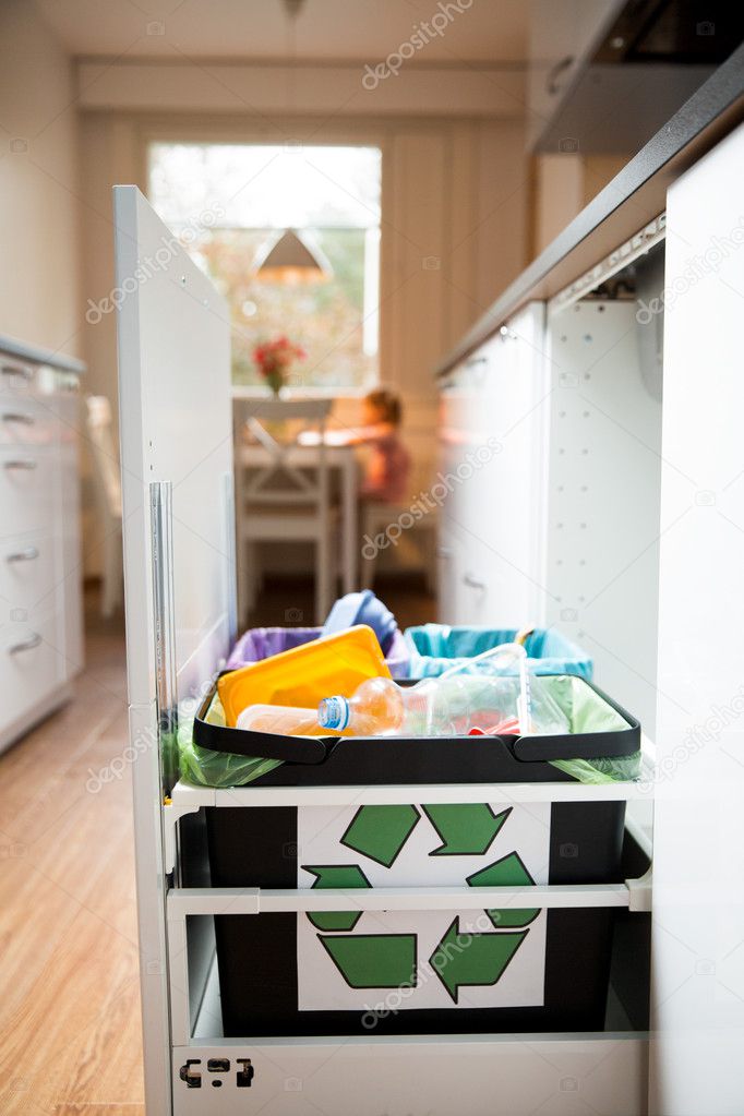 Three trash bins with sorted garbage in kitchen with segregated