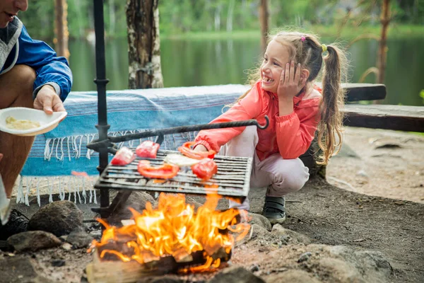 湖の岩場の海岸の森でバーベキューをしている男と彼の小さな娘は 焼きパン マシュマロを作っています フィンランドを探検する家族 北欧の夏の風景 — ストック写真