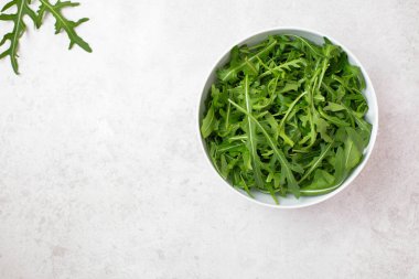 Beyaz bardakta roka ile sağlıklı ve taze salata. Organik ve doğal gıda konsepti. Hafif arkaplan. Üst Manzara. Düz yatıyordu. Boşluğu kopyala. 