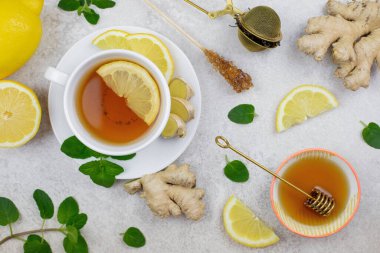 Beyaz bardakta zencefilli çay, limon dilimi, nane şekeri, tatlım. Beyaz arka planda sıcak ve sağlıklı bir içecek. Bağışıklık sistemi savunması, C vitamini. Üst görünüm. 