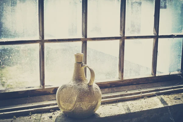 Retro filtered an old dusty clay bottle by window — Stock Photo, Image