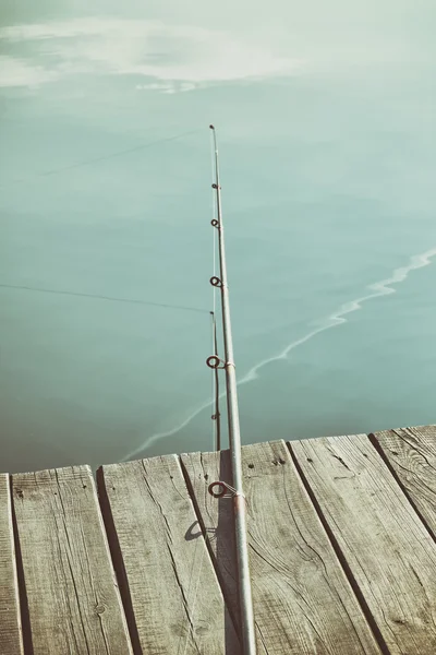 Retro toned fishing rod on a wooden pier Royalty Free Stock Images