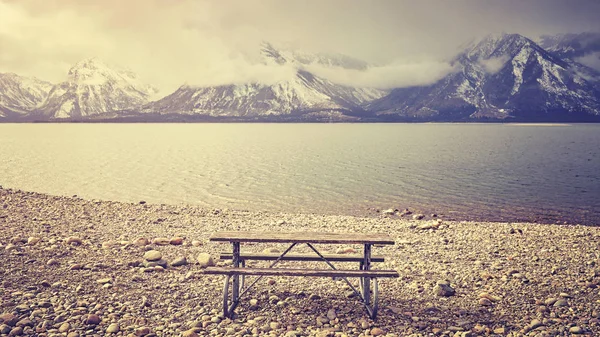 Retro stiliserad en tom bänk med vacker utsikt över sjön. — Stockfoto