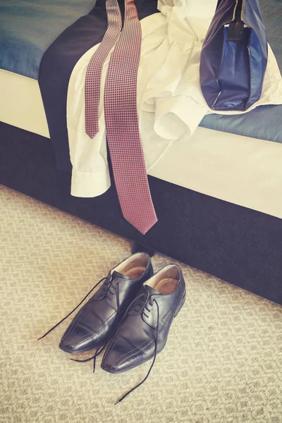 Retro stylizované mužské černé kožené boty a oblečení na postel. — Stock fotografie