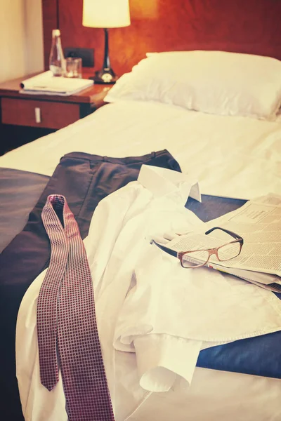 Elegante Kleidung, Zeitung und Brille auf einem Hotelbett. — Stockfoto